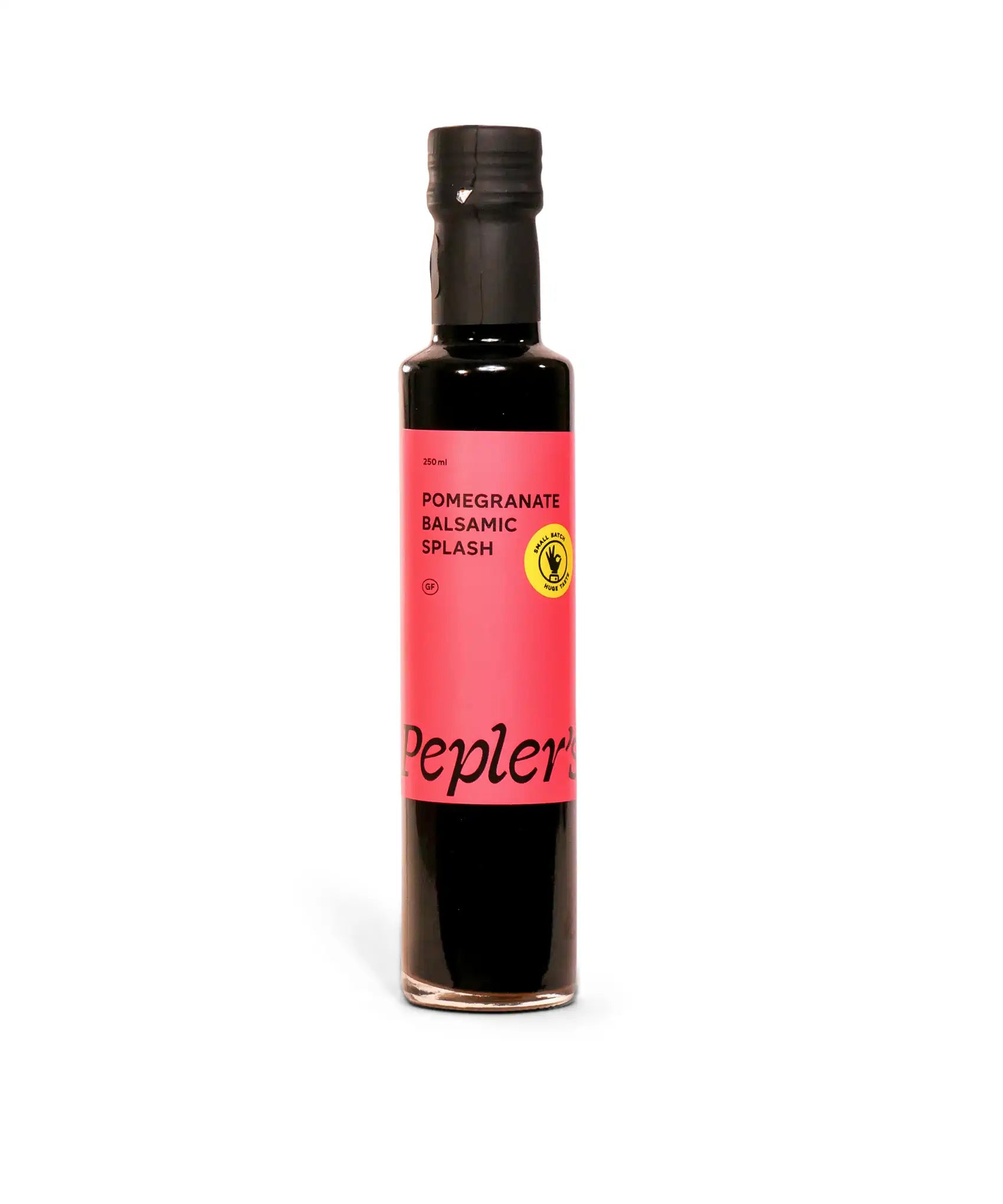 A bottle of Pomegranate Balsamic Splash by Pepler's, featuring a black glass design with a striking pink label. The label prominently displays "Pomegranate Balsamic Splash" and "250 ml," along with a gluten-free symbol and a note about it being a small batch product. The bottle stands against a plain white background, emphasising its modern and appealing packaging.