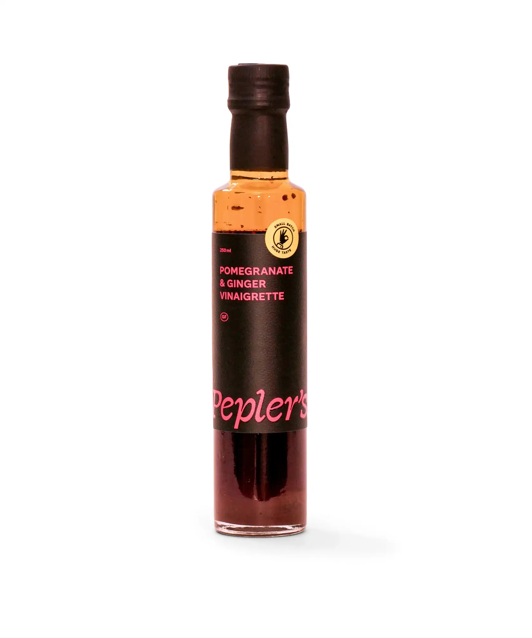 A bottle of Pepler's Pomegranate & Ginger Vinaigrette, labeled with bold black text on a bright pink background. The bottle is transparent with a dark brown liquid inside, and features a small round seal that indicates "small batch, big taste." The total volume of the bottle is 250 ml. The background is plain and white, emphasising the product.