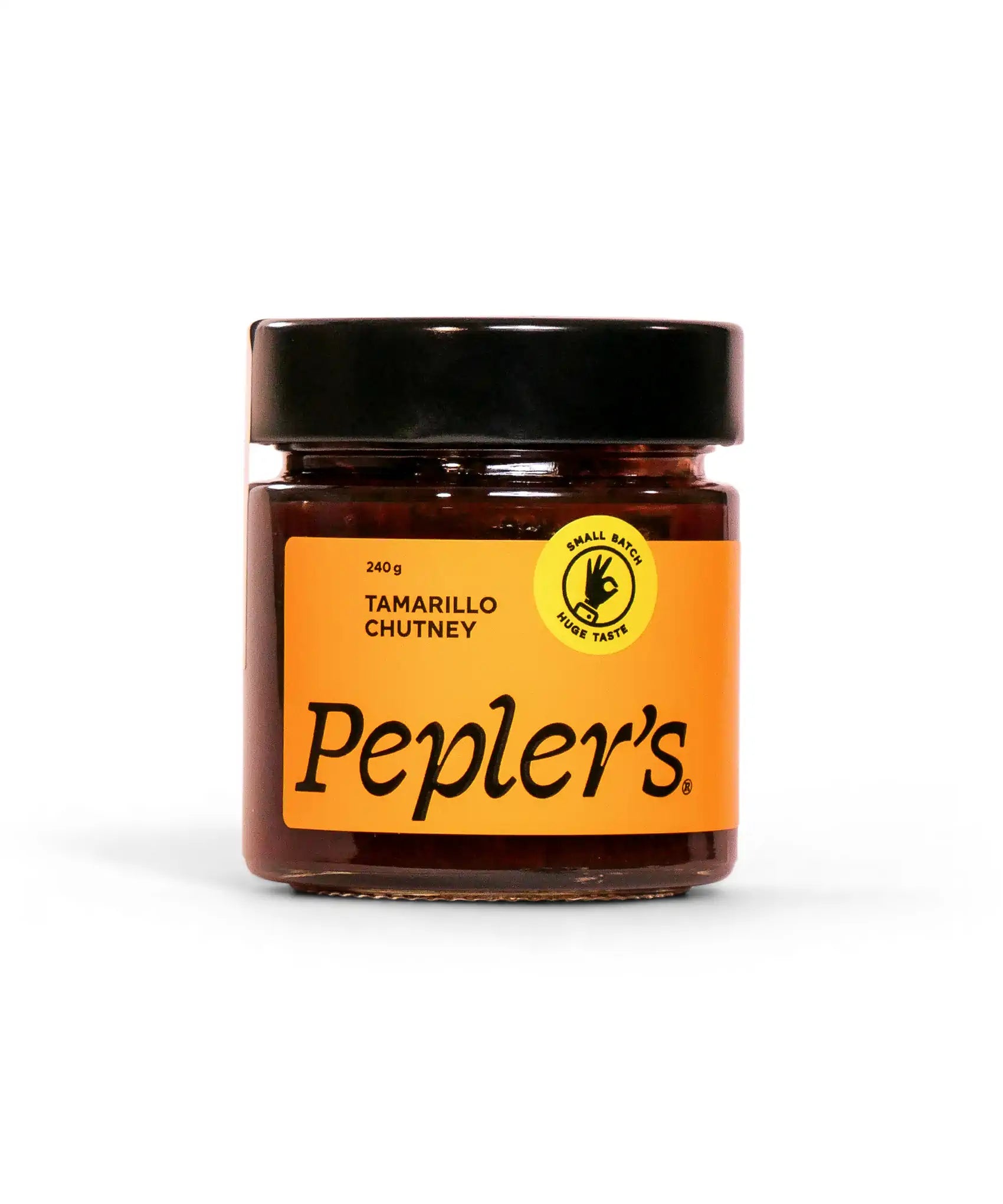 Glass jar of Pepler's tamarillo chutney, labeled with a bright orange design, featuring the product name, weight of 240g, and a yellow seal indicating small batch production. The background is plain white, highlighting the jar's contents and branding.