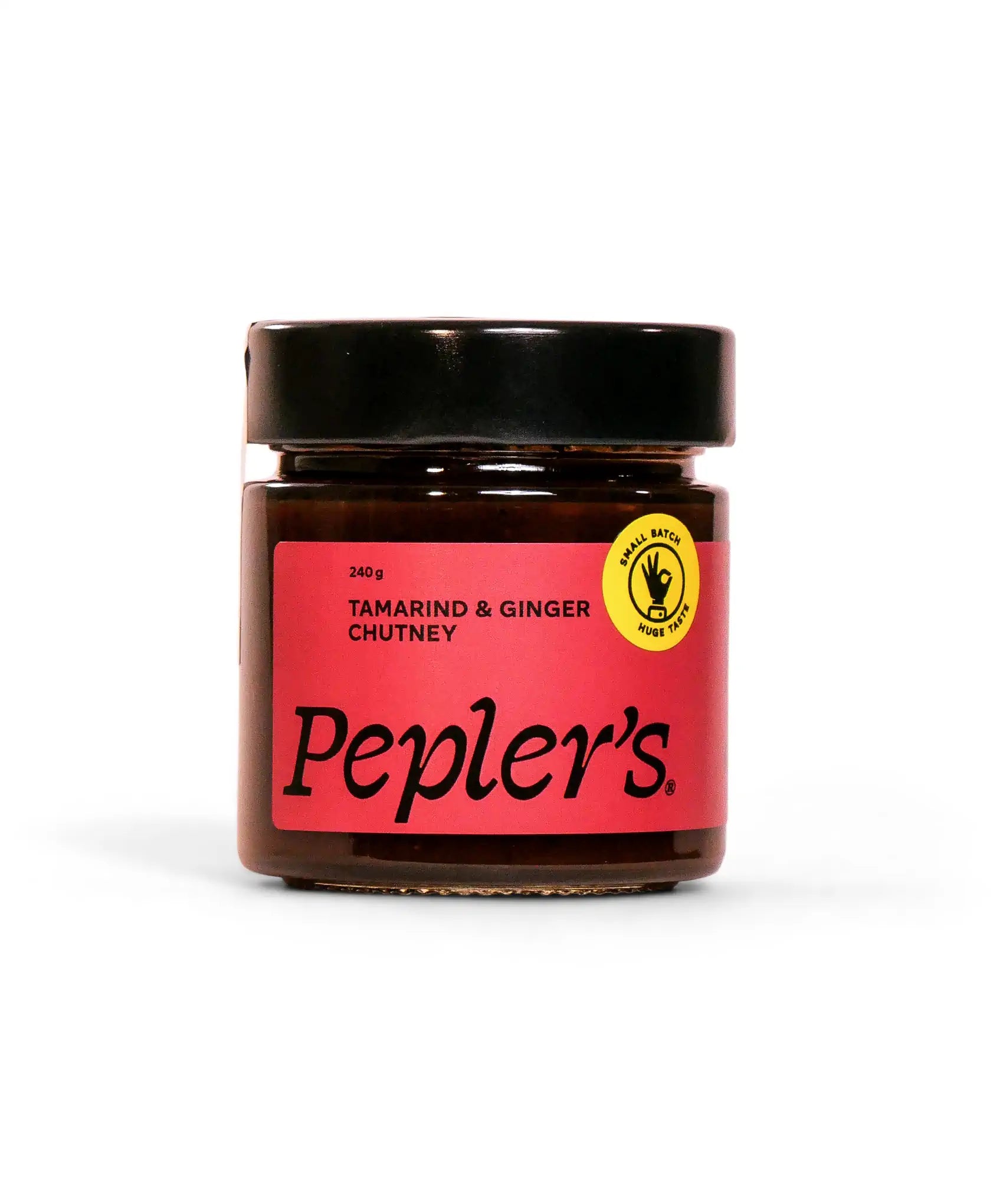 A jar of Pepler's tamarind and ginger chutney, labeled with a bright pink and black design. The jar weighs 240 grams and features a small batch production emblem with a yellow circular label. The background is a soft white, highlighting the chutney jar's design.